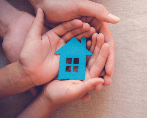 Image of hands holding a blue paper house