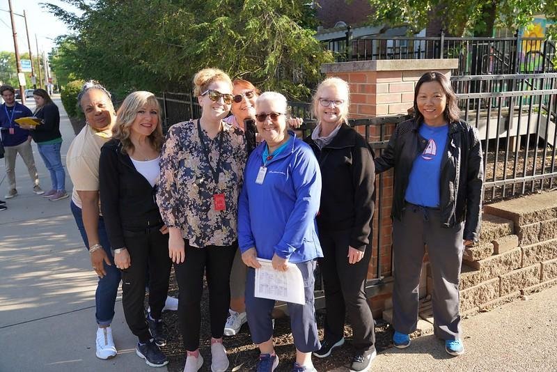 A group of smiling teachers standing outside of the The Day School entrance waiting for students to arrive on the first day of school.